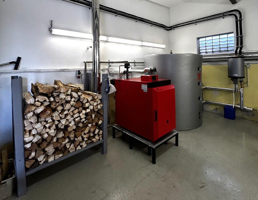 Holzvergaserkessel IBC GK-7k-öko 🔥 in einem modernen Heizraum mit Holzstapel 🌲 und Warmwasserspeicher.